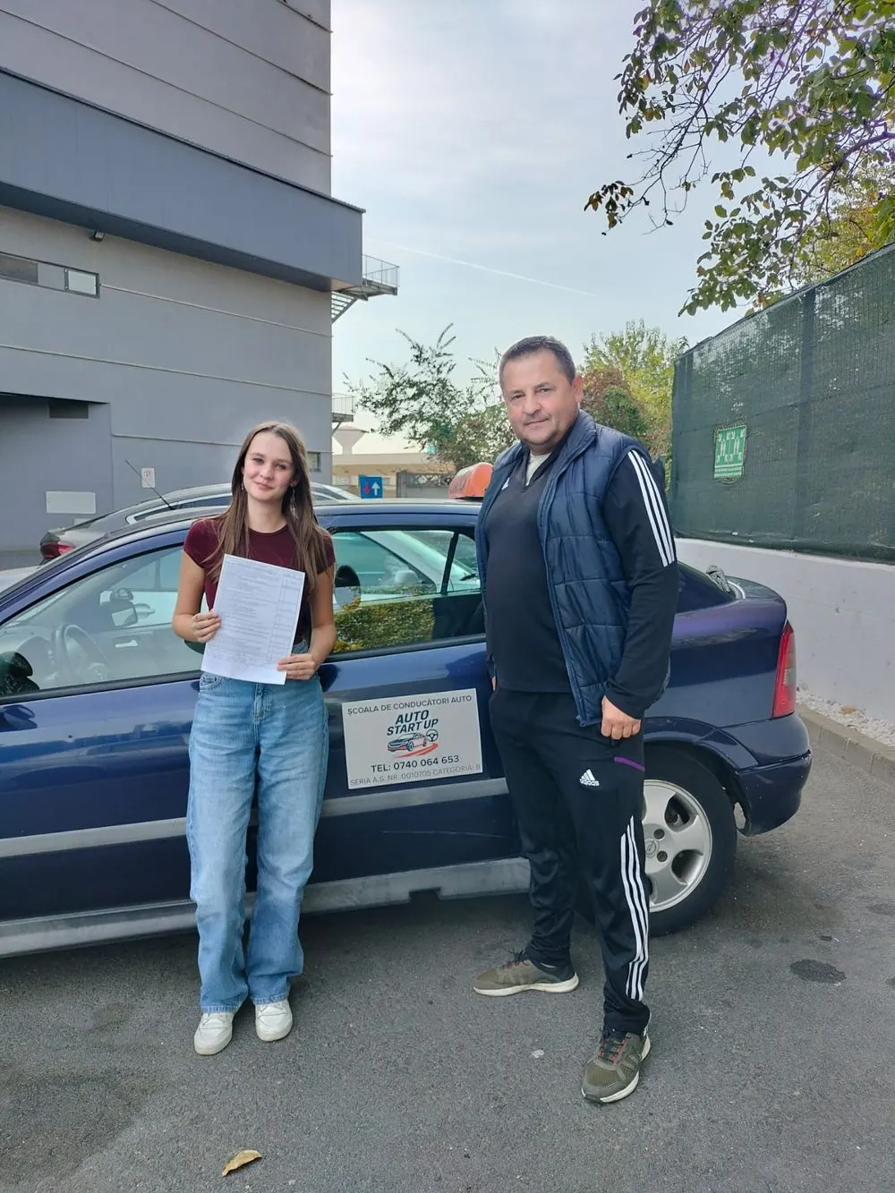 Cursantă și instructor lângă mașina albastră