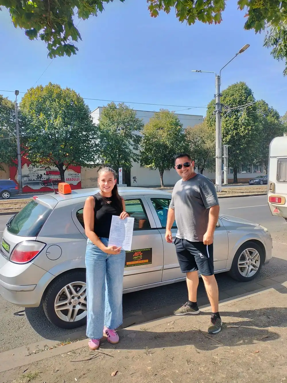 Cursantă și instructor lângă mașina argintie