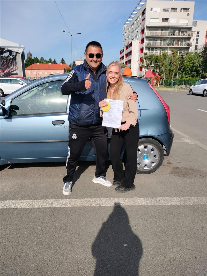 Cursantă și instructor lângă mașina de școală